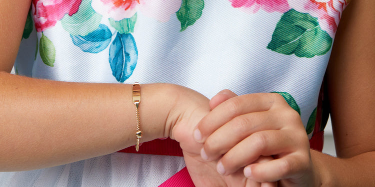Goldenes Gravurarmband mit Ring an Kinderhand, traditionelles Taufgeschenk