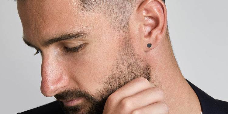 Mann mit Bart trägt schwarze runde Ohrstecker